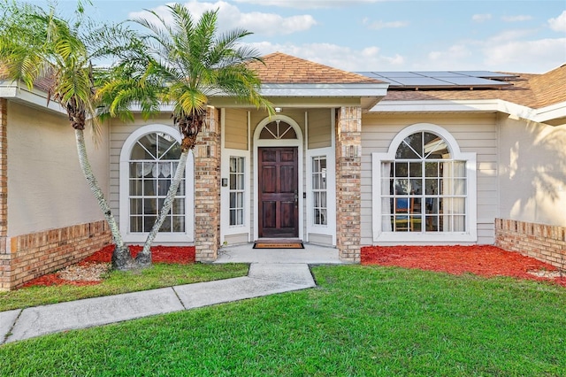 doorway to property with a yard and solar panels