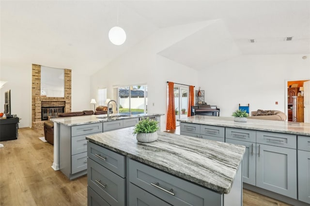 kitchen featuring lofted ceiling, a center island, light wood-type flooring, and gray cabinetry