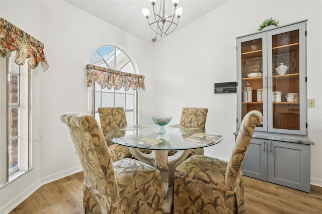 dining area with light hardwood / wood-style floors, an inviting chandelier, and a textured ceiling