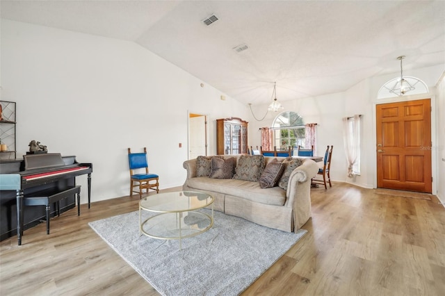 living room with lofted ceiling, light hardwood / wood-style flooring, and an inviting chandelier