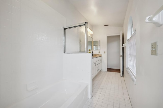 bathroom with vanity, lofted ceiling, a bath, and tile patterned flooring