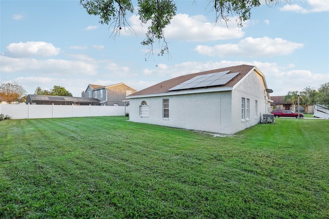 back of property with a yard and solar panels