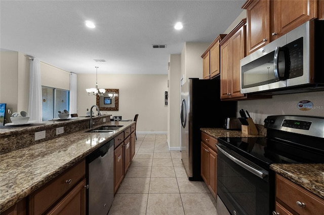 kitchen with dark stone countertops, an inviting chandelier, sink, and stainless steel appliances