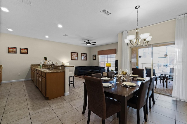 dining area with light tile patterned floors, ceiling fan with notable chandelier, and sink