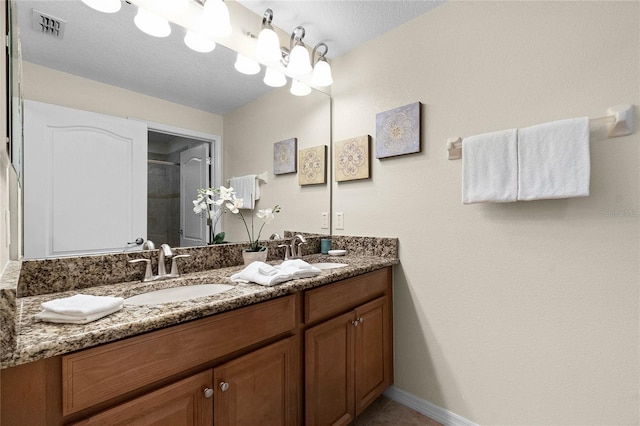 bathroom with walk in shower, vanity, and a textured ceiling