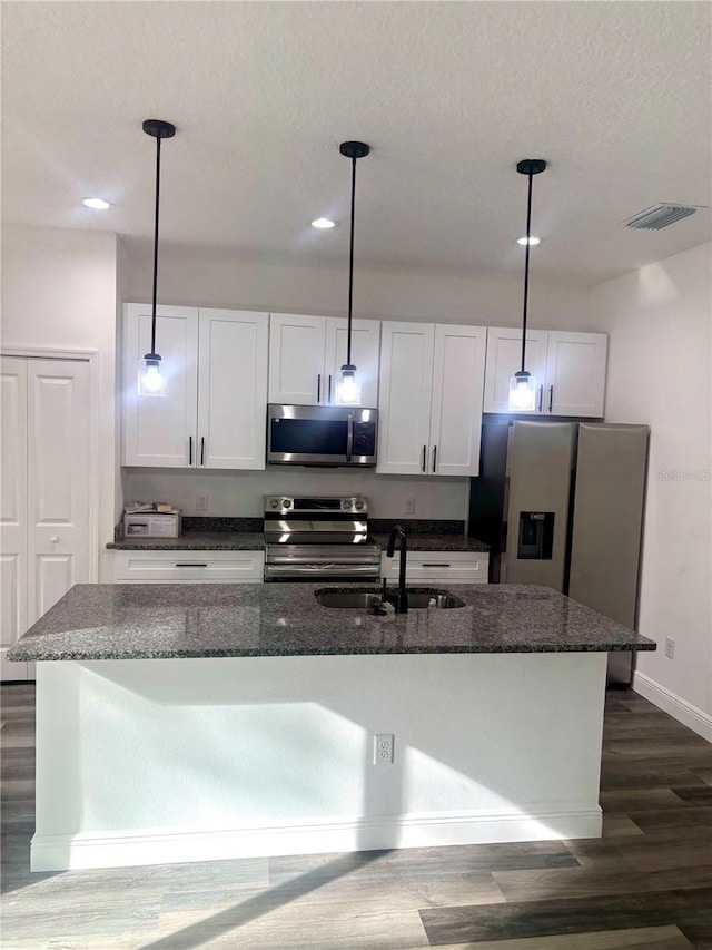 kitchen with stainless steel appliances, sink, decorative light fixtures, white cabinetry, and a kitchen island with sink