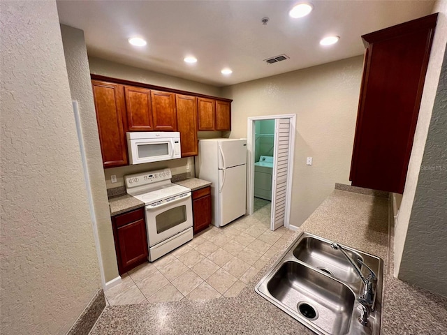 kitchen with washer / dryer, white appliances, sink, and light tile patterned floors