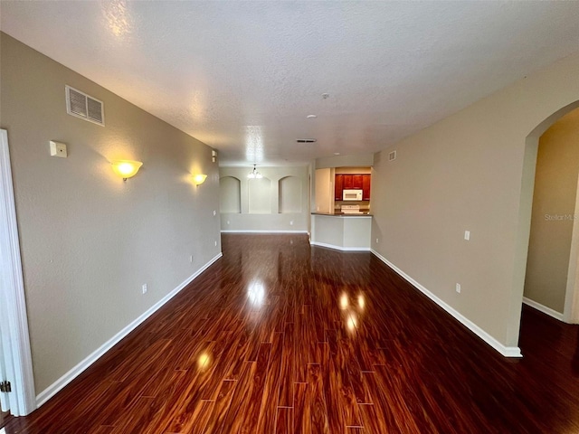 unfurnished living room featuring dark wood-type flooring and a textured ceiling