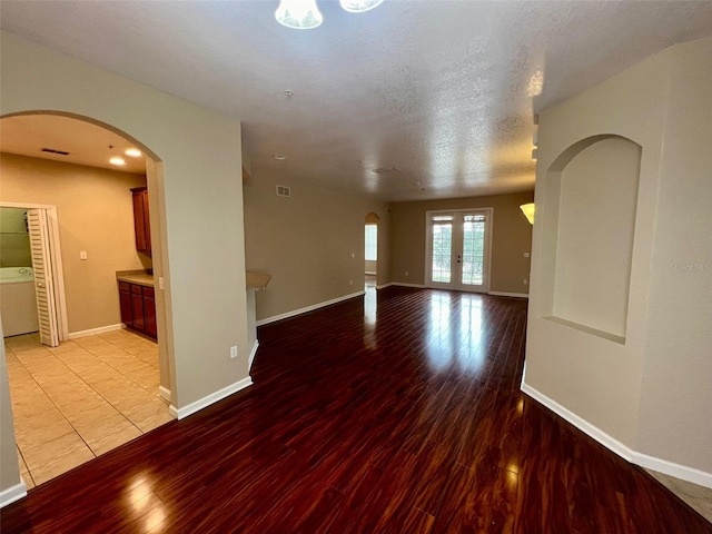 empty room featuring light wood-type flooring, french doors, washer / clothes dryer, and a textured ceiling