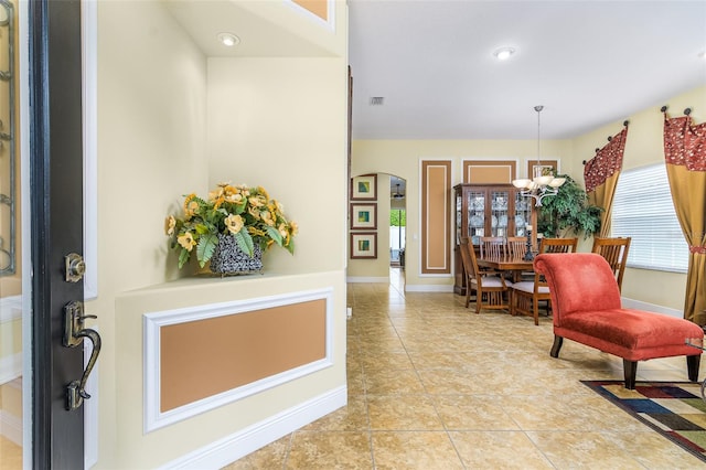 tiled foyer featuring an inviting chandelier