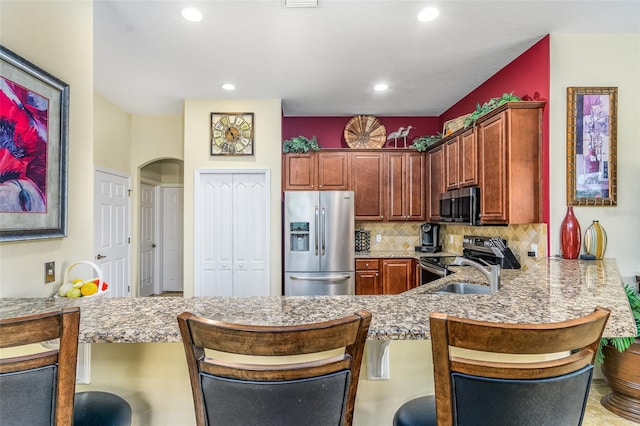 kitchen featuring decorative backsplash, sink, kitchen peninsula, a breakfast bar area, and appliances with stainless steel finishes