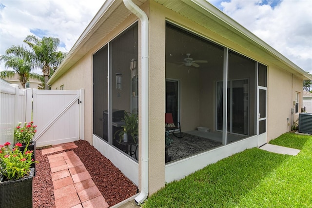 exterior space with central air condition unit, a sunroom, a lawn, and ceiling fan