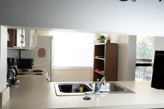 kitchen with a sink, light countertops, and white appliances