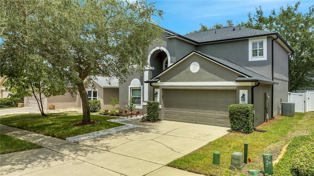 front of property with a garage, a front lawn, and central AC