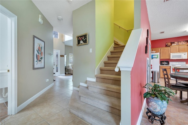 stairs with a textured ceiling and tile patterned floors