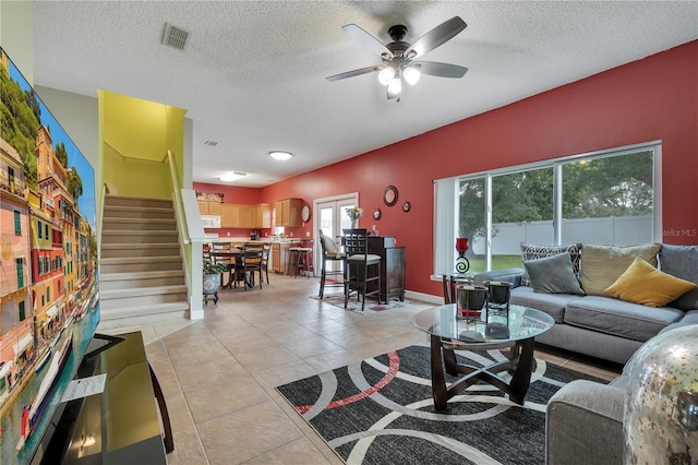 living room featuring ceiling fan, light tile patterned floors, and a textured ceiling