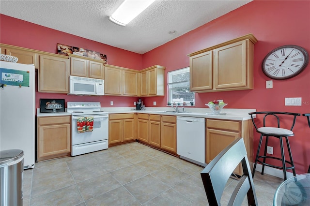 kitchen featuring white appliances, light tile patterned floors, a textured ceiling, light brown cabinetry, and sink