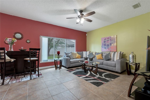 tiled living room with indoor bar, ceiling fan, and a textured ceiling