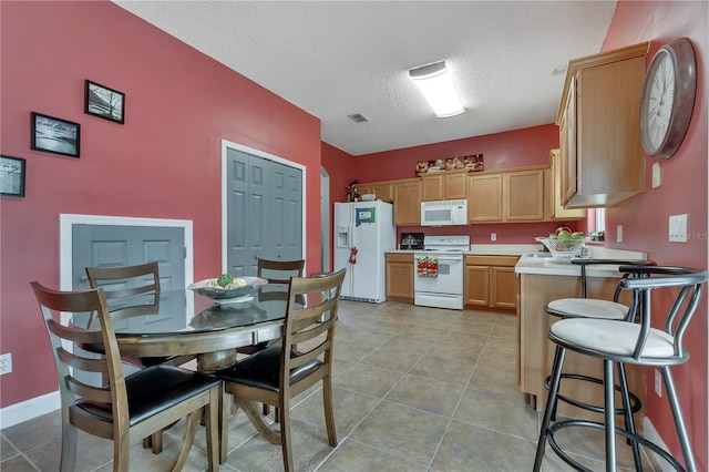 kitchen with a textured ceiling, white appliances, and light tile patterned floors