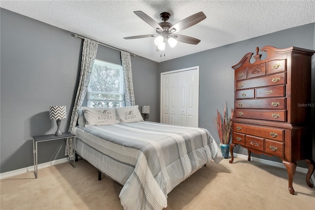 bedroom featuring ceiling fan, a textured ceiling, a closet, and light carpet