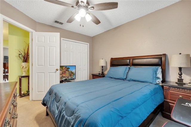 bedroom with a closet, a textured ceiling, lofted ceiling, ceiling fan, and light carpet