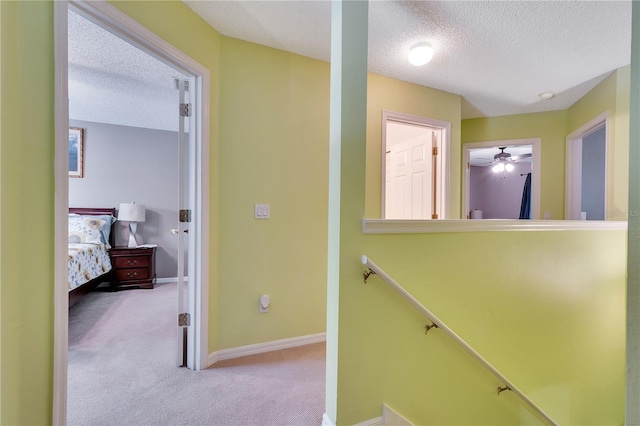 hallway featuring a textured ceiling and light colored carpet