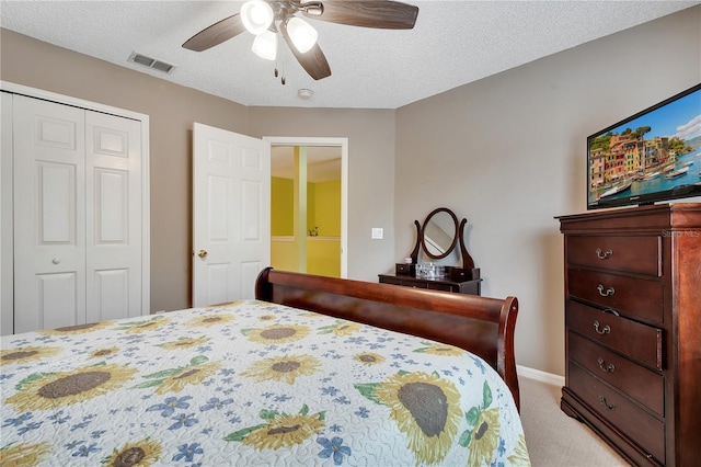 carpeted bedroom with a textured ceiling, ceiling fan, and a closet