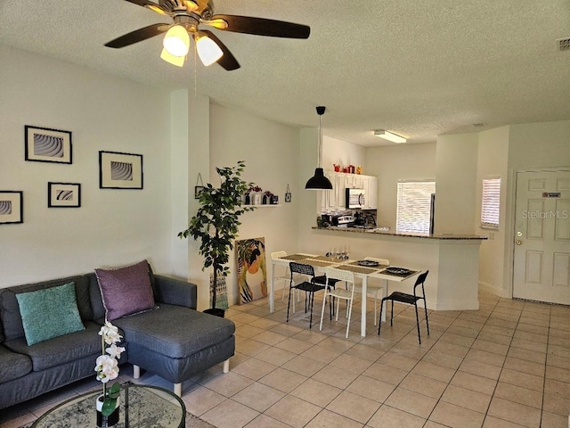 tiled living room featuring ceiling fan and a textured ceiling