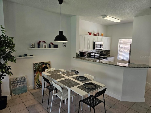 dining area with a textured ceiling, light tile patterned flooring, and sink