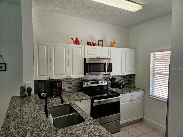 kitchen with a textured ceiling, sink, white cabinetry, decorative backsplash, and stainless steel appliances