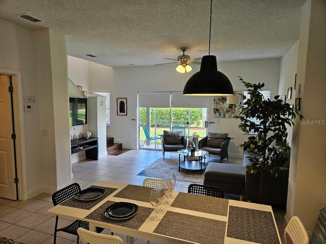 living room with ceiling fan, light tile patterned flooring, and a textured ceiling