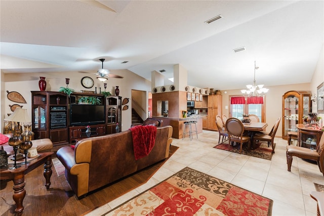 tiled living room with ceiling fan with notable chandelier and lofted ceiling