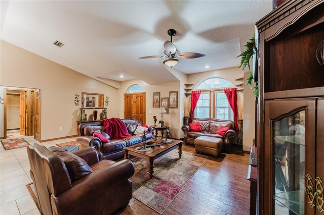 living room featuring light hardwood / wood-style flooring, lofted ceiling, ceiling fan, and a textured ceiling