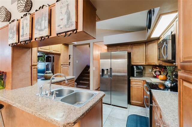 kitchen with appliances with stainless steel finishes, a center island with sink, sink, and light tile patterned floors