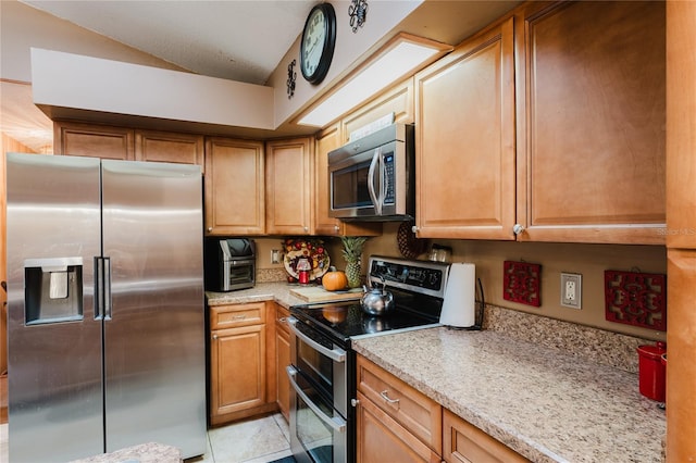 kitchen with light stone countertops, appliances with stainless steel finishes, and light tile patterned floors