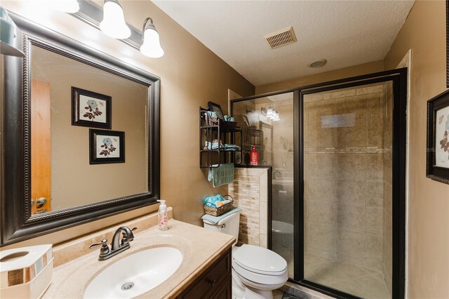 bathroom with a textured ceiling, an enclosed shower, vanity, and toilet