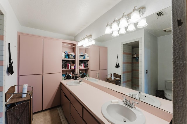 bathroom featuring vanity, tiled shower, a textured ceiling, tile patterned floors, and toilet