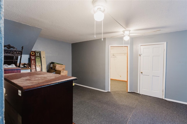 interior space featuring ceiling fan, a textured ceiling, and dark colored carpet