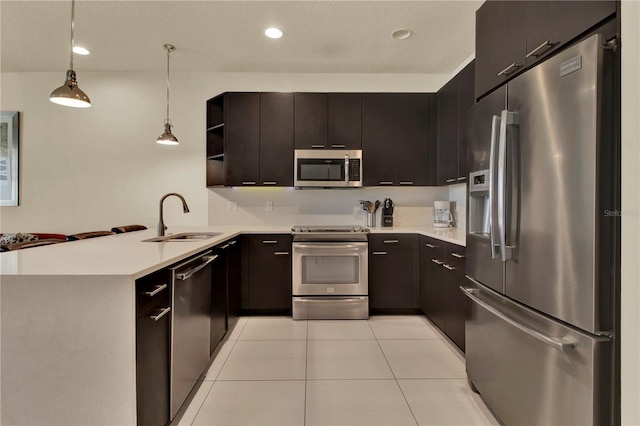 kitchen featuring hanging light fixtures, kitchen peninsula, light tile patterned floors, stainless steel appliances, and sink