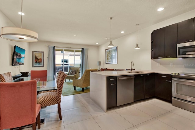 kitchen featuring light tile patterned floors, sink, kitchen peninsula, decorative light fixtures, and appliances with stainless steel finishes