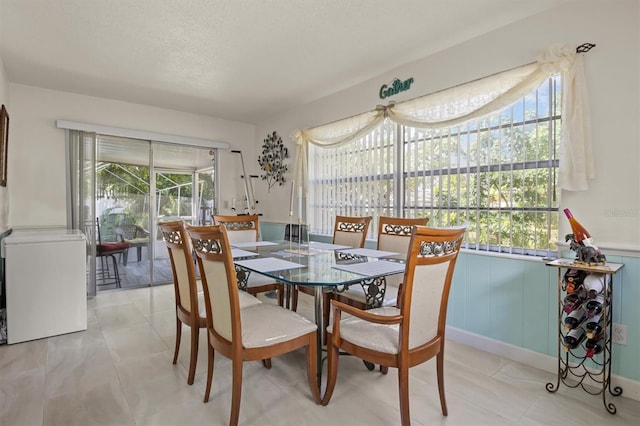 dining area featuring plenty of natural light, light tile patterned floors, and a textured ceiling