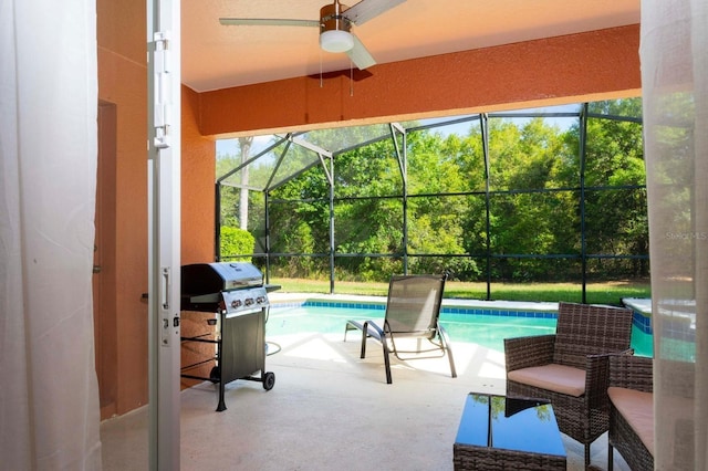 view of patio featuring ceiling fan, area for grilling, and glass enclosure