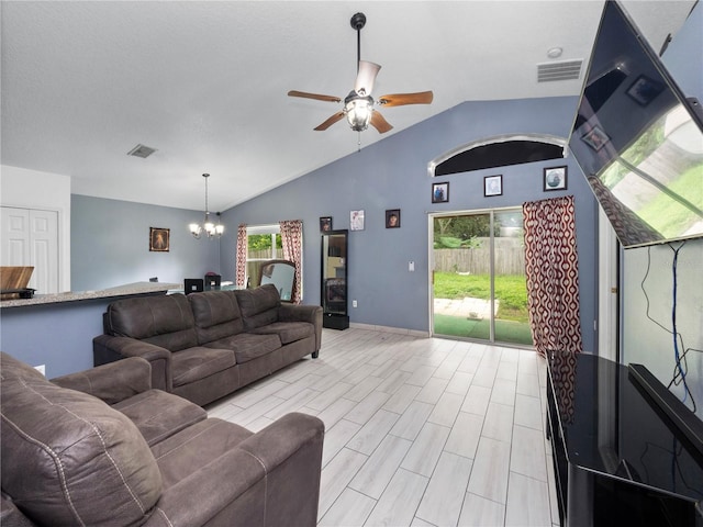 living room with ceiling fan with notable chandelier, vaulted ceiling, and a wealth of natural light