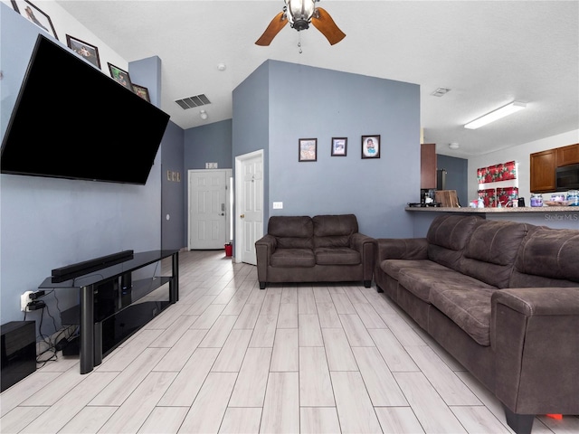 living room featuring ceiling fan, lofted ceiling, and light wood-type flooring