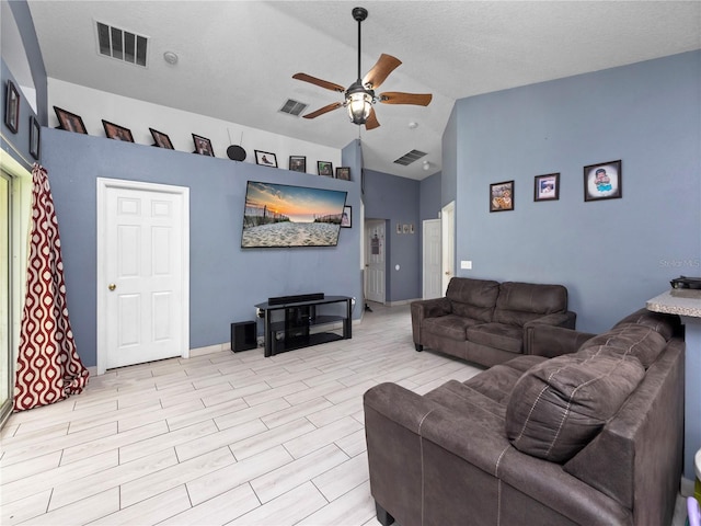 living room featuring light wood-type flooring, vaulted ceiling, ceiling fan, and a textured ceiling