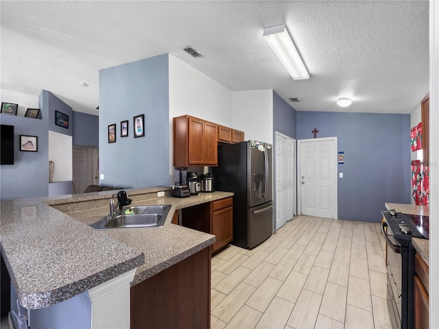 kitchen featuring stainless steel appliances, kitchen peninsula, sink, and a textured ceiling