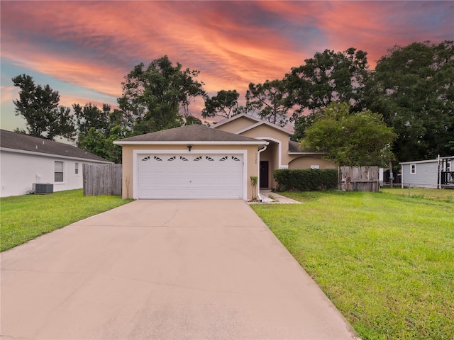 view of front of property with a lawn, central AC, and a garage