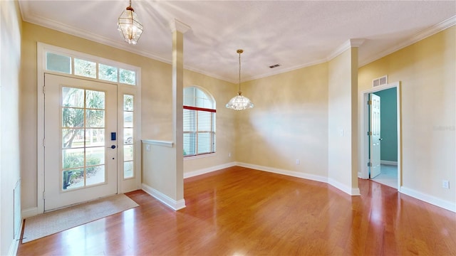 doorway with ornamental molding, a notable chandelier, and wood-type flooring