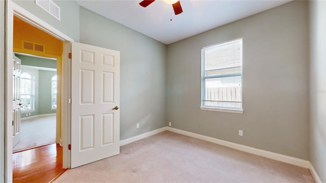 unfurnished room with light carpet, a healthy amount of sunlight, and ceiling fan