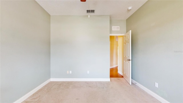 empty room featuring light carpet and a textured ceiling